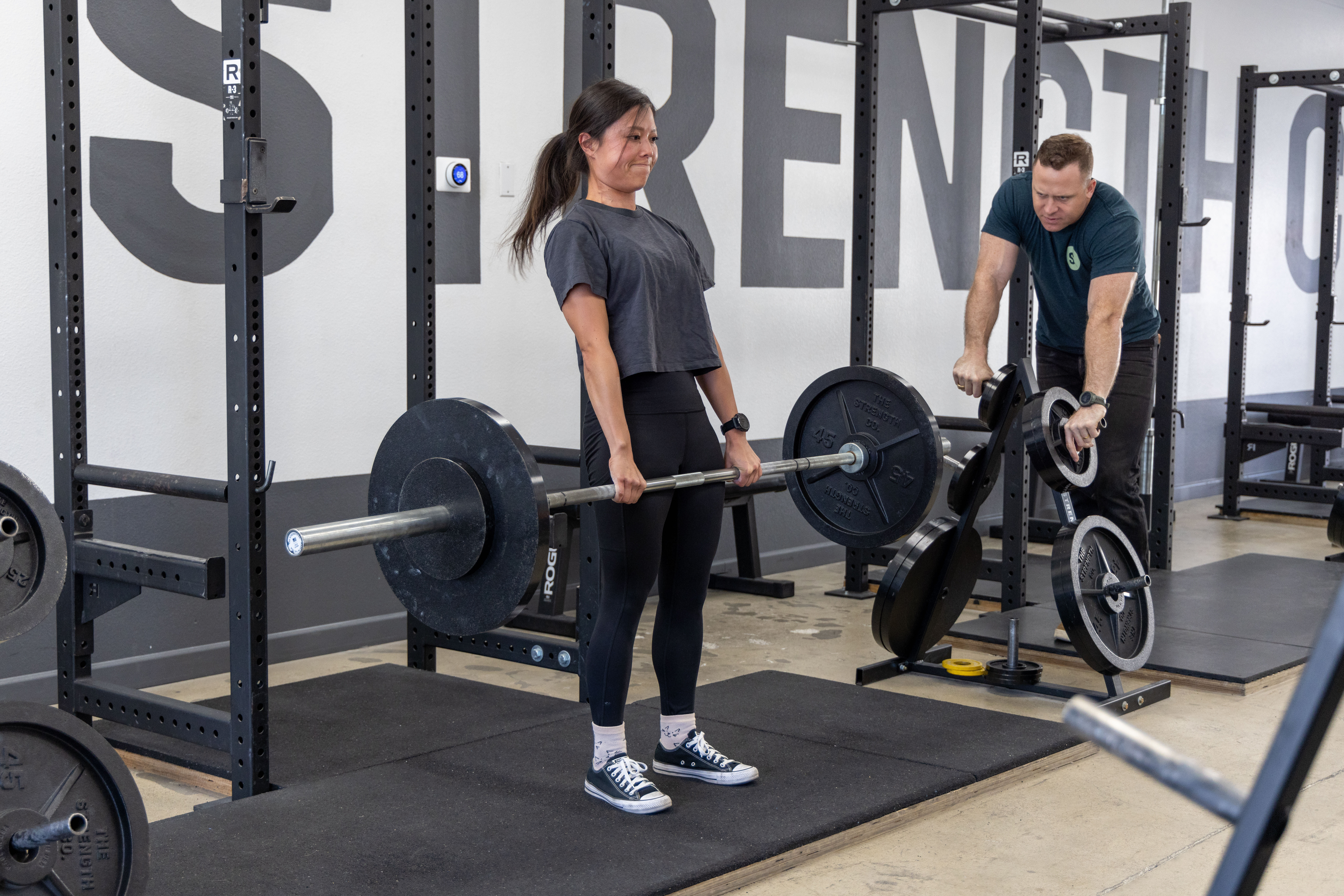 A woman pulling a barbell in a deadlift.