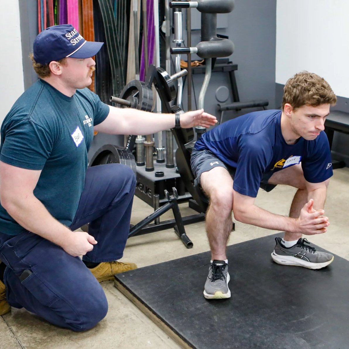 Starting Strength coach helping a member with squat form
