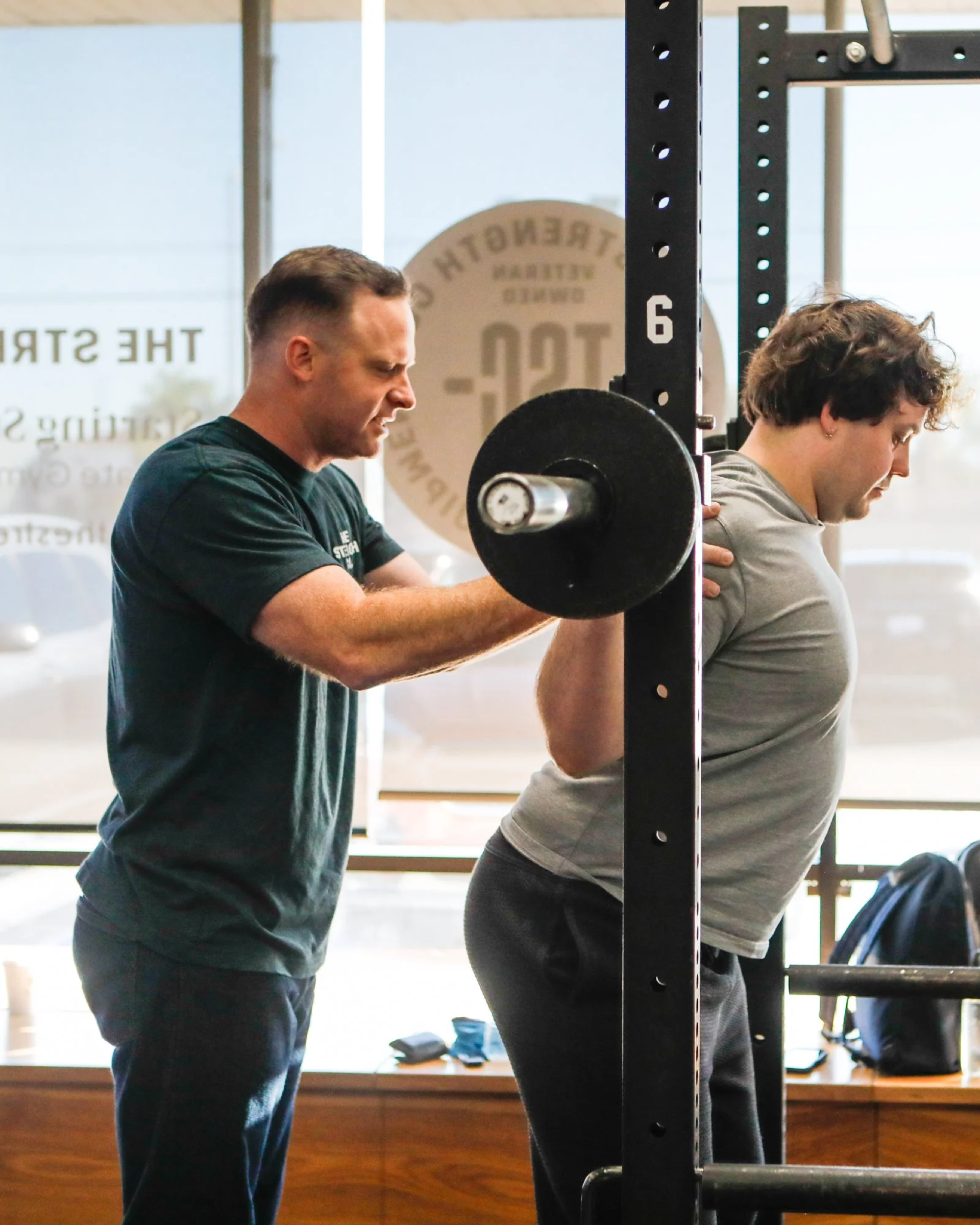 Coach spotting a member on the squat rack