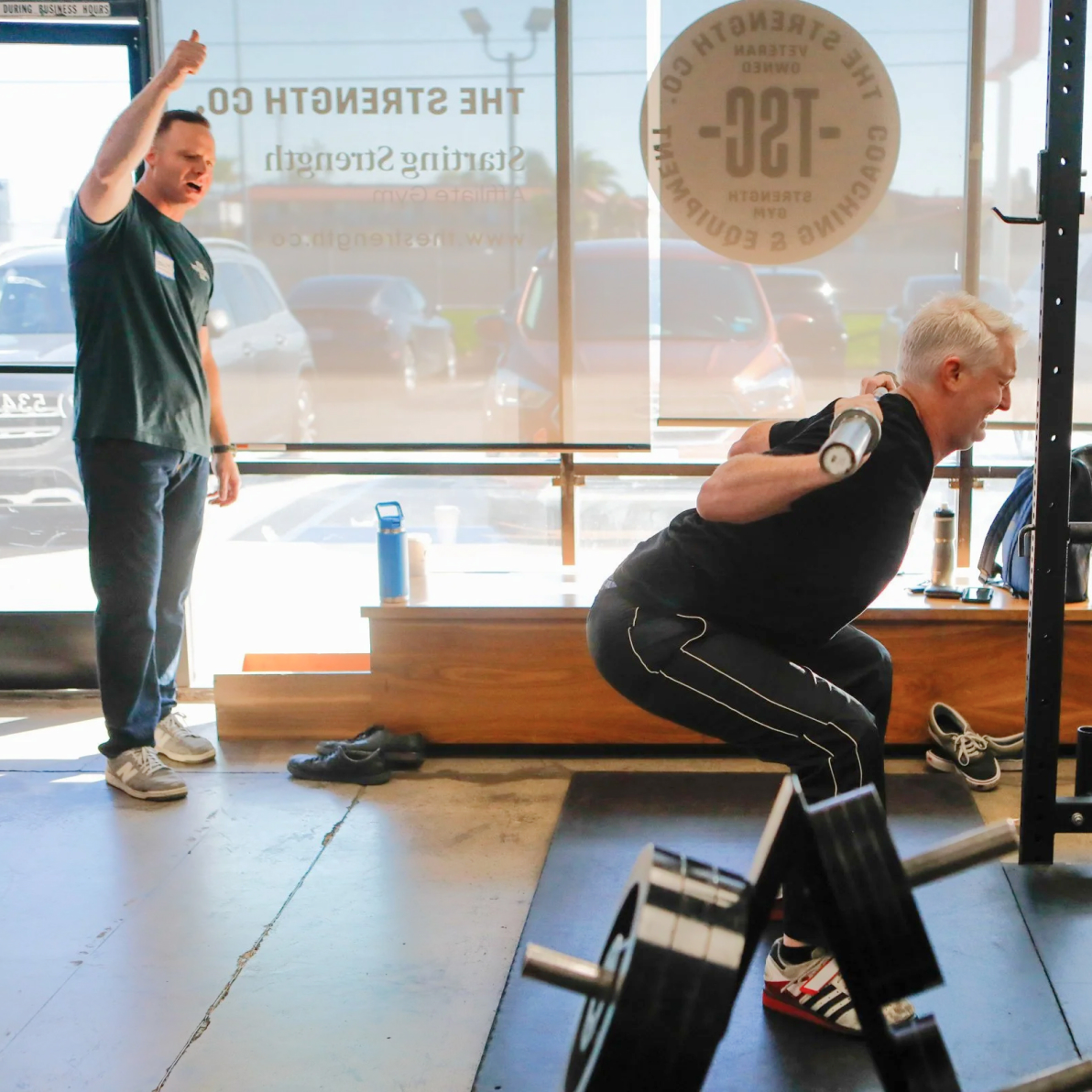 Coach guiding a member through a barbell squat at The Strength Co.