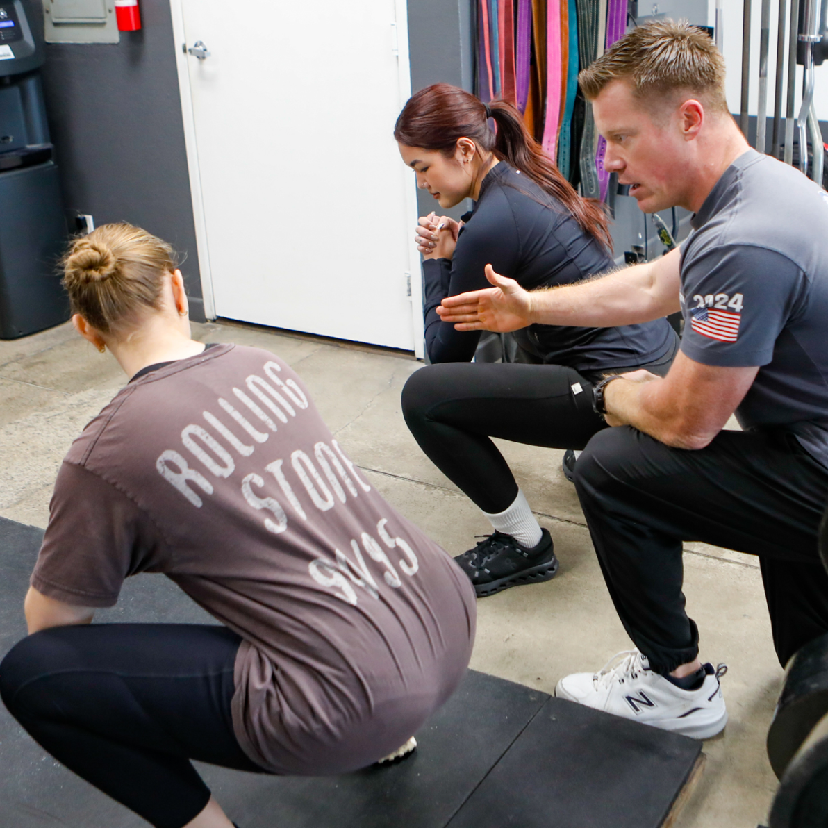 Coach instructing members on squat technique at The Strength Co.