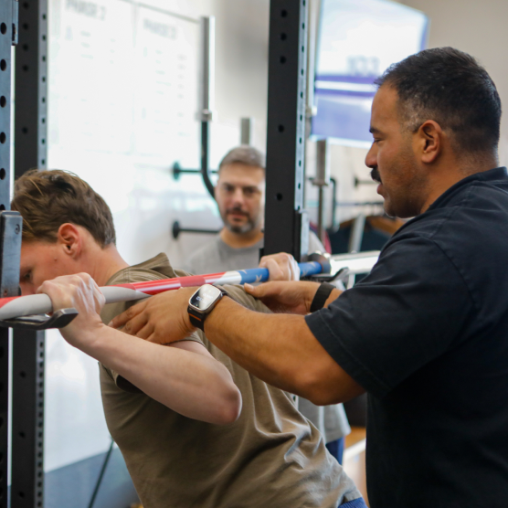 Coach spotting squat at The Strength Co.