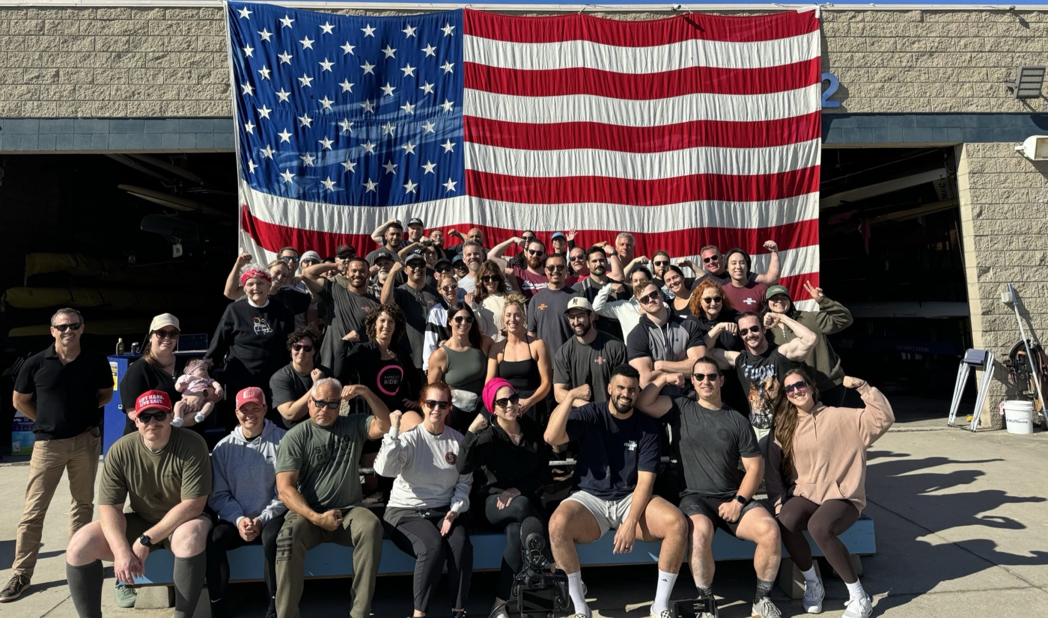 Lifters and families flexing in front of a giant American flag at The Strength Co. Turkey Pull